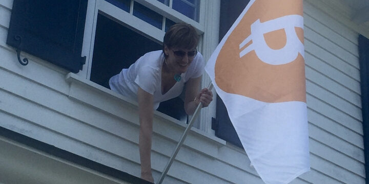 woman putting on a Bitcoin flag on her window